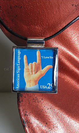 Official I Love You Deaf awareness stamp bezel set and resin sealed.